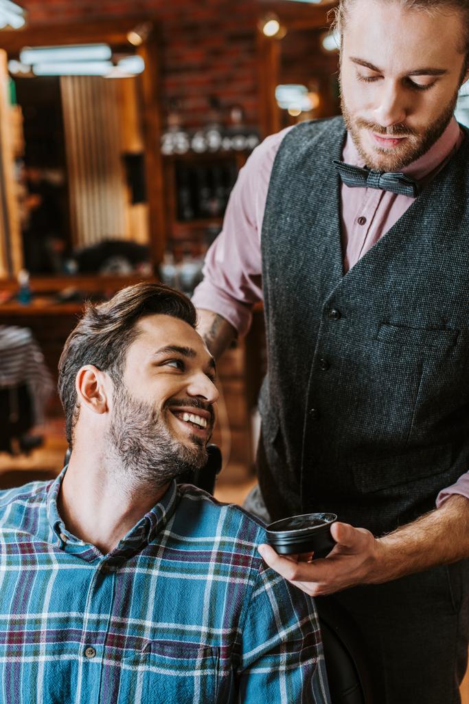 красивий перукар тримає банку з чорним волоссям помпою біля щасливого чоловіка
  - Фото, зображення