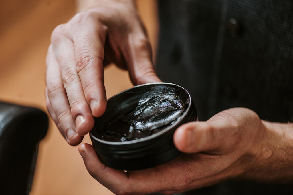 vista cortada do homem segurando jar com cabelo preto pomade
  - Foto, Imagem