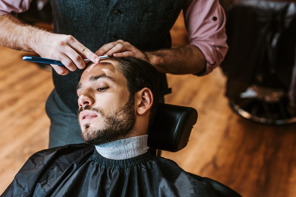 barbeiro segurando navalha afiada perto de homem bonito
  - Foto, Imagem