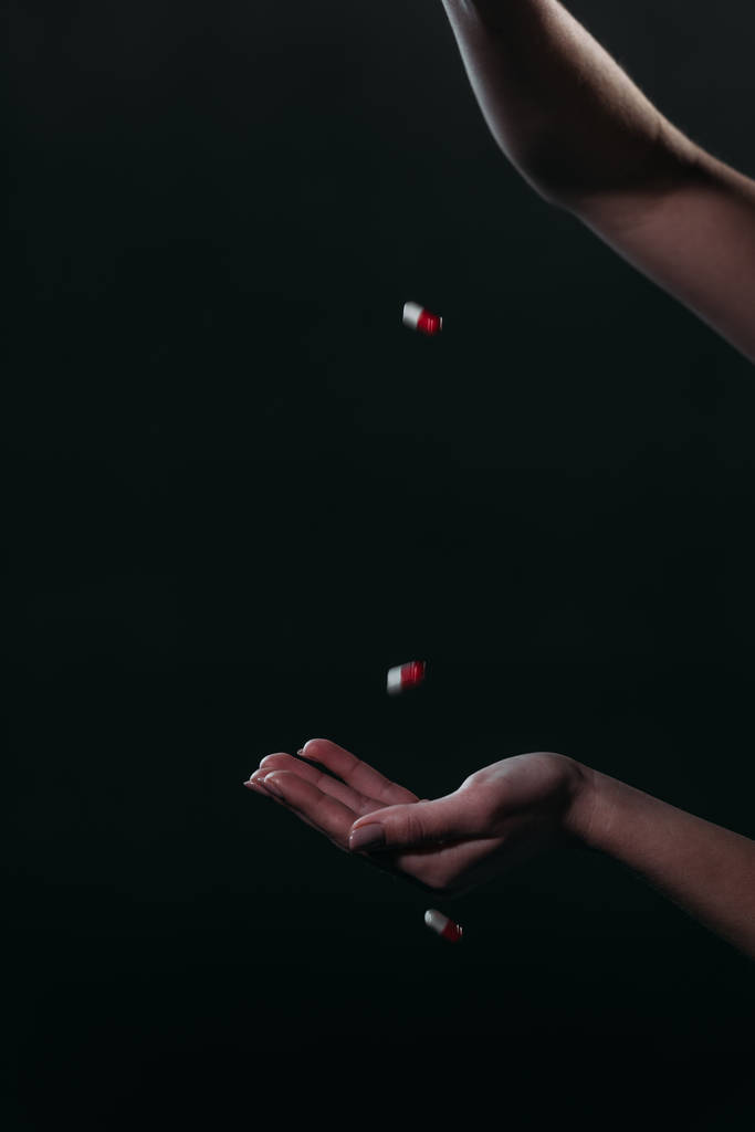 bijgesneden beeld van vrouw gooien pillen in open hand, terwijl gaan om zelfmoord te plegen geïsoleerd op zwart - Foto, afbeelding