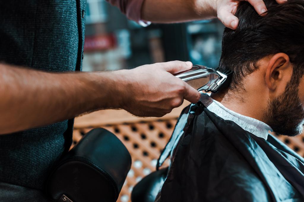 selektywny ostrość fryzjer gospodarstwa trymer podczas stylizacji włosów człowieka  - Zdjęcie, obraz