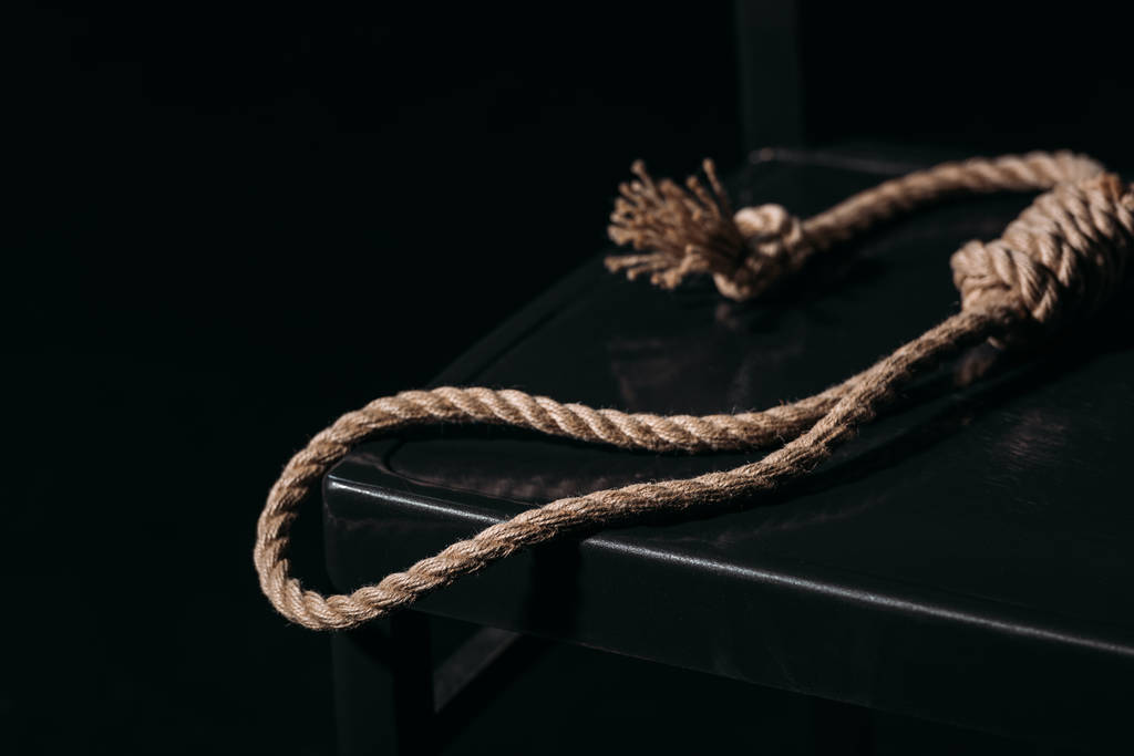 touw strop op stoel op zwarte achtergrond, zelfmoord preventie concept - Foto, afbeelding