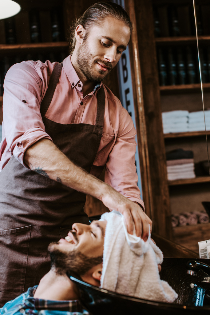 selective focus of handsome barber holding white towel near head of happy man - Photo, Image