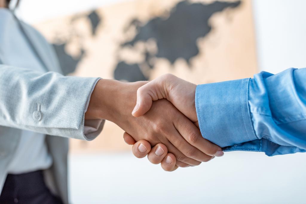 cropped view of travel agent and client shaking hands in office - 写真・画像