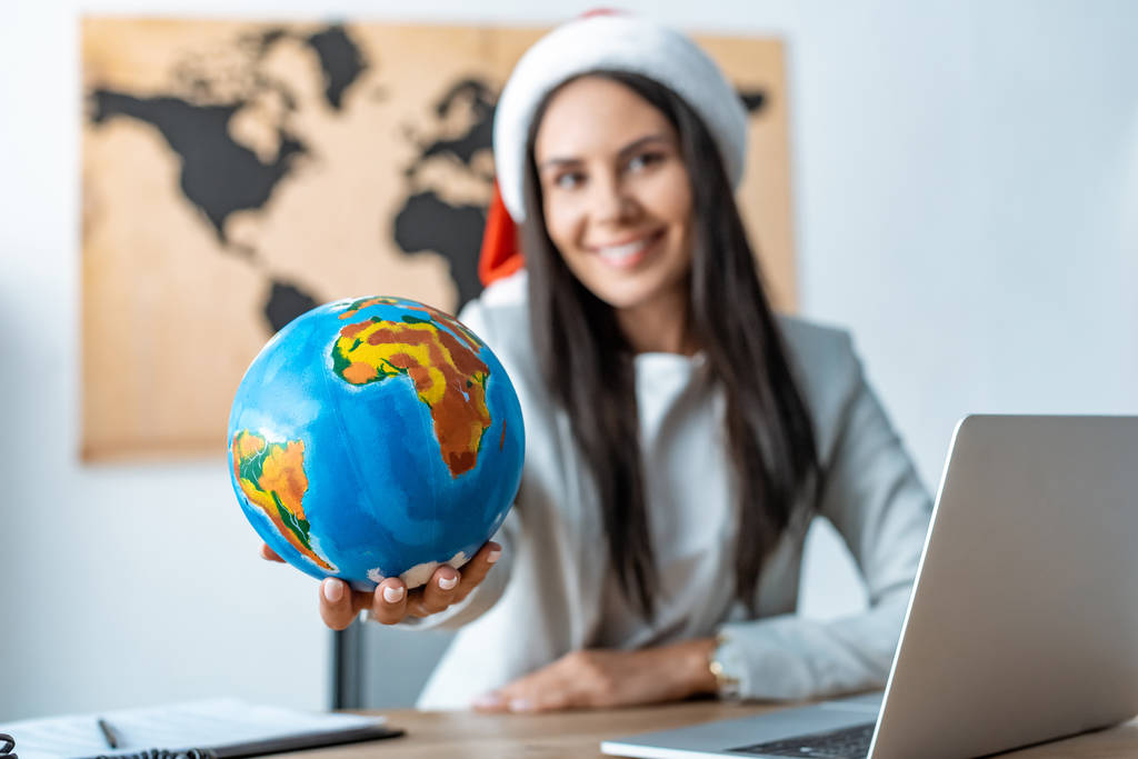 cheerful travel agent showing globe and smiling at camera - Photo, Image