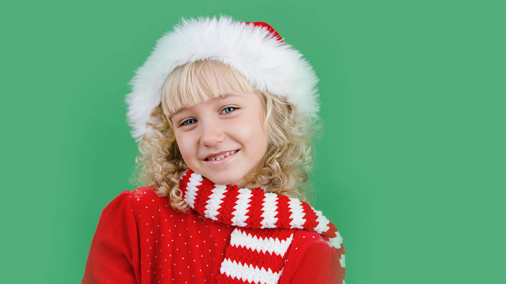 onnellinen pieni tyttö Santa hattu hymyilevä ja katsot kameraa kirkkaan vihreä eloisa väri tausta, Hyvää joulua käsite
 - Valokuva, kuva