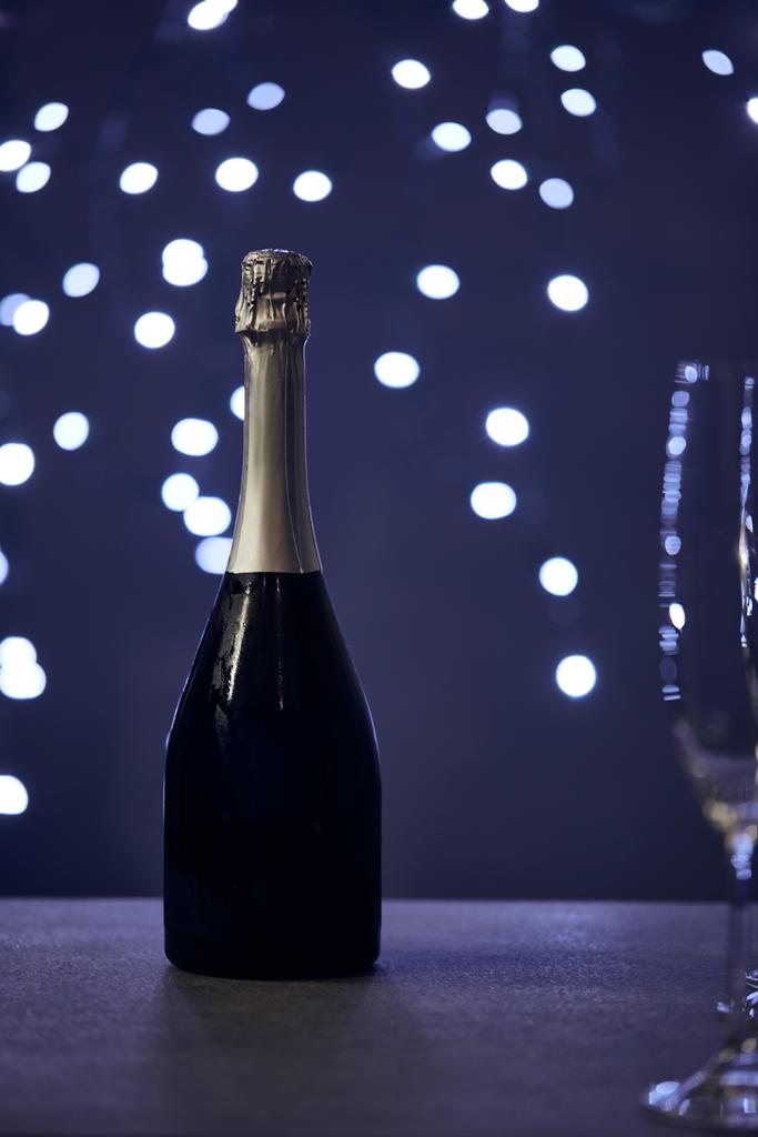 シャンパンボトルとクリスマスライト付きガラスのセレクトフォーカス｜bokeh - 写真・画像