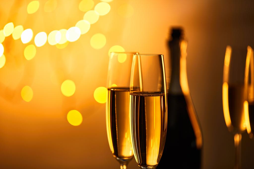 copos de vinho espumante com garrafa borrada e luzes de Natal amarelas
 - Foto, Imagem