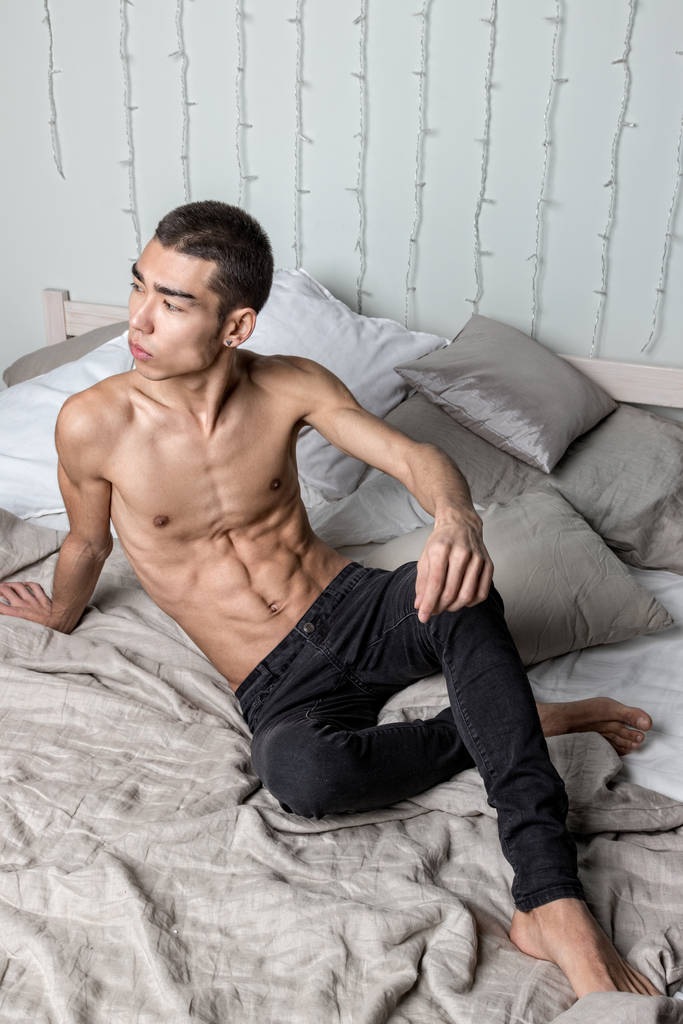 Fiatal jóképű férfi pihen az ágyban. Szexi meztelen srác pihen - Fotó, kép