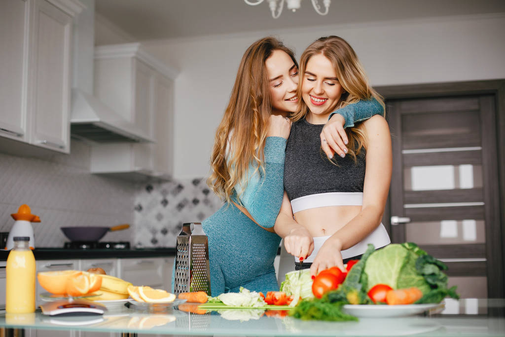 Két sport-lány a konyhában, zöldségekkel - Fotó, kép