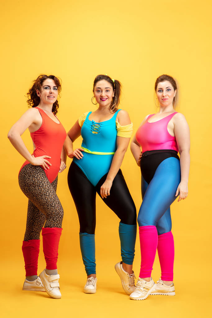 Fiatal kaukázusi plusz méret női modellek képzés sárga háttér - Fotó, kép
