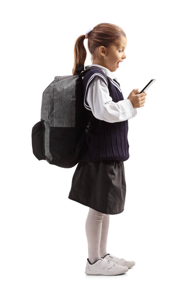Nadšený školačka stojící a dívající se na mobilní telefon - Fotografie, Obrázek