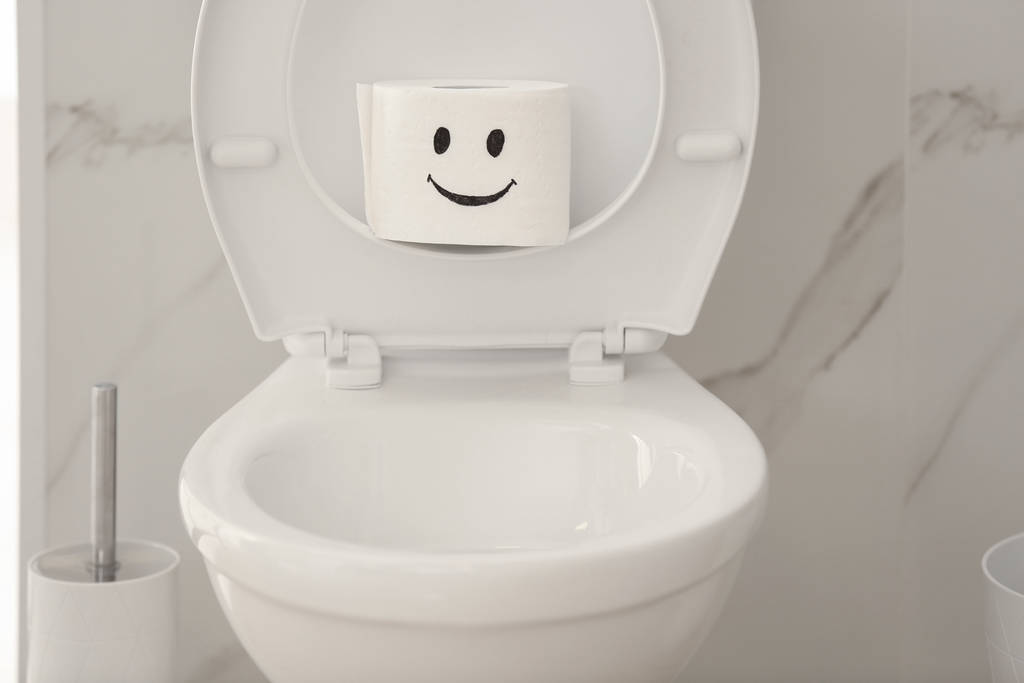 浴室のトイレのボウルに面白い顔を持つ紙のロール - 写真・画像