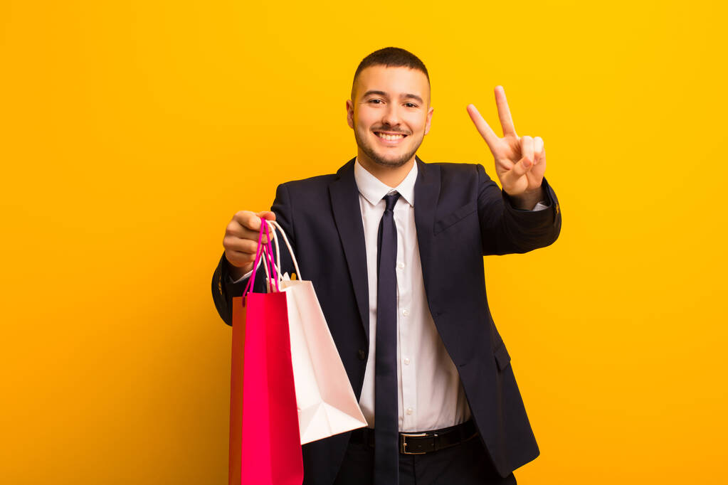 fiatal jóképű üzletember ellen lapos háttér bevásárló táskák - Fotó, kép