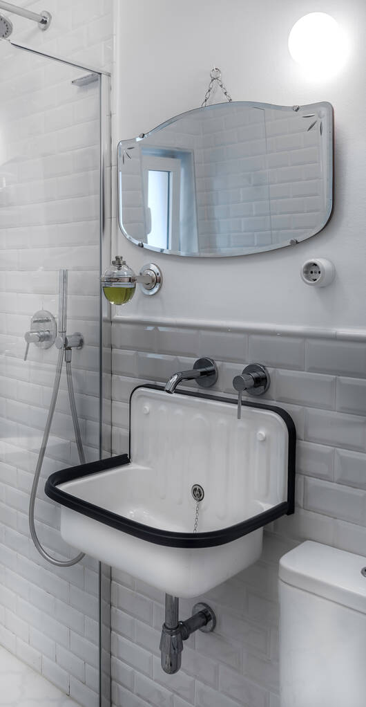 Vintage fürdőszoba belső acél és klasszikus csempe. Eredeti medence mosogató fehér lakkozott fém és fekete gumi. Antik tükör. - Fotó, kép