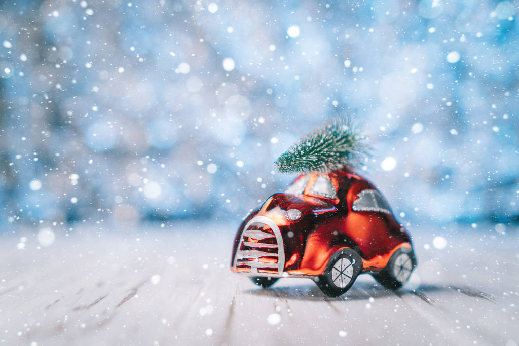 kleines rotes Spielzeugauto trägt einen Weihnachtsbaum - Foto, Bild