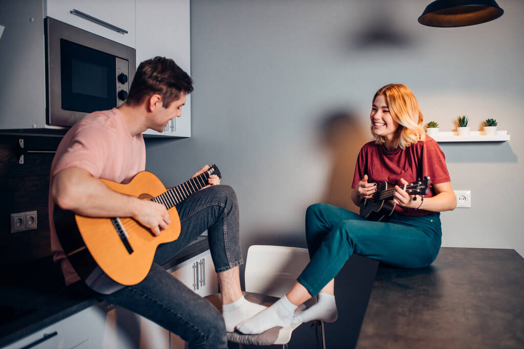 pareja caucásica tocando la guitarra y ukelele en casa
 - Foto, imagen