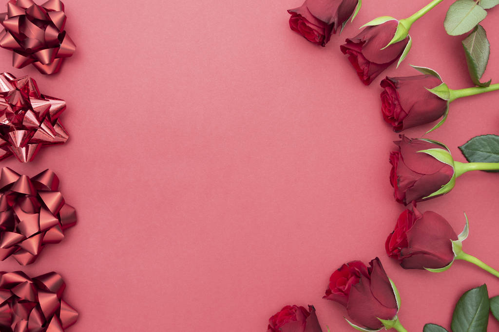 Κόκκινα τριαντάφυλλα δώρο, κορδέλα υποκλίσεις πάνω από ροζ φόντο επίπεδη θέσει. Ημέρα του Αγίου Βαλεντίνου, Γενέθλια αφηρημένη φόντο με αντίγραφο χώρου. - Φωτογραφία, εικόνα