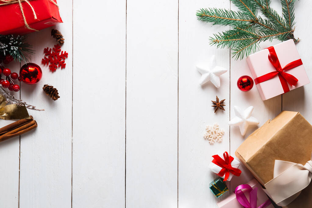 Прекрасна різдвяна композиція на дерев'яному білому тлі з різдвяними подарунковими коробками, засніженими ялиновими гілками, хвойними шишками, сухофруктами кориці, святковою прикрасою, карамельною паличкою. Новий рік. Вид зверху, простір для копіювання
. - Фото, зображення