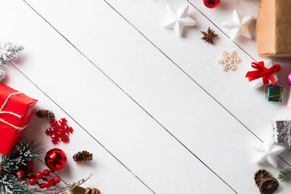 クリスマスギフトボックス、雪のモミの枝、針葉樹コーン、シナモンドライフルーツ、休日の装飾、キャラメルスティックと木製の白い背景に美しいクリスマスの組成物。新年。トップビュー、コピースペース. - 写真・画像