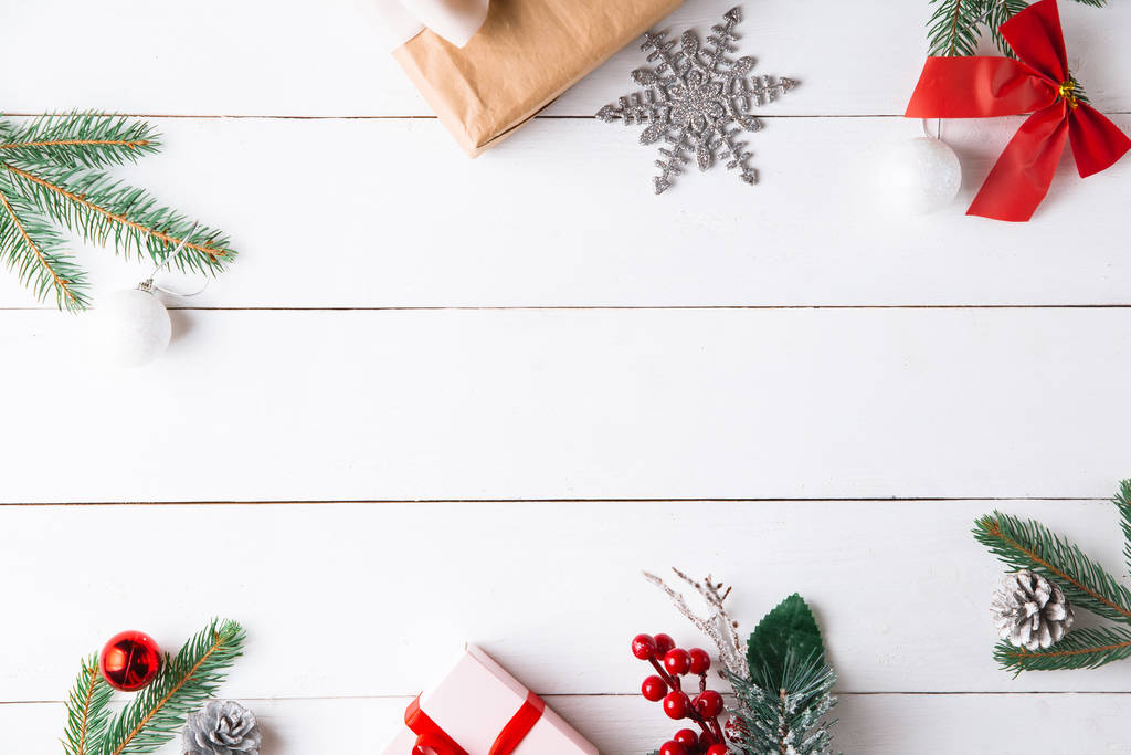 クリスマスギフトボックス、雪のモミの枝、針葉樹コーン、シナモンドライフルーツ、休日の装飾、キャラメルスティックと木製の白い背景に美しいクリスマスの組成物。新年。トップビュー、コピースペース. - 写真・画像
