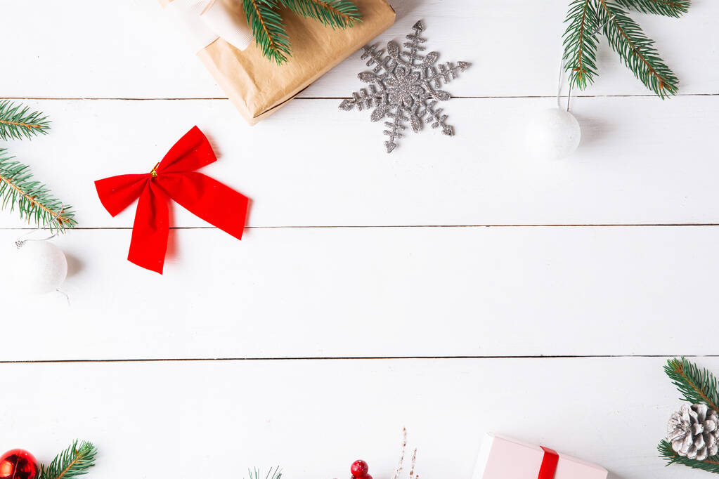 Όμορφη χριστουγεννιάτικη σύνθεση σε ξύλινο λευκό φόντο με χριστουγεννιάτικα κουτιά δώρων, χιονισμένα κλαδιά ελάτης, κώνους κωνοφόρων, κανέλα αποξηραμένα φρούτα, διακόσμηση διακοπών, καραμέλα ραβδί. Πρωτοχρονιά. Πάνω όψη, αντιγραφή χώρου. - Φωτογραφία, εικόνα