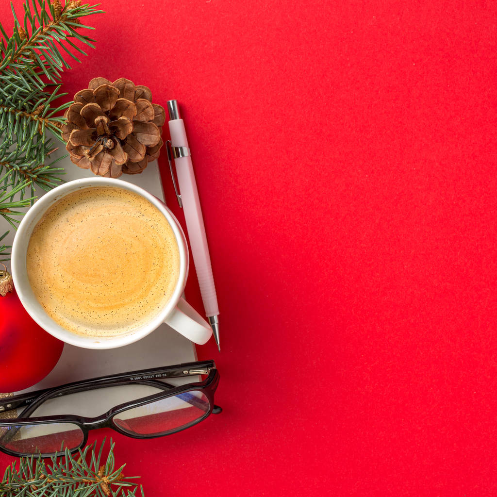 Karácsonyi díszek a Jegyzettömb, toll, szemüveg és csésze kávét piros munkaterület felülnézet - Fotó, kép