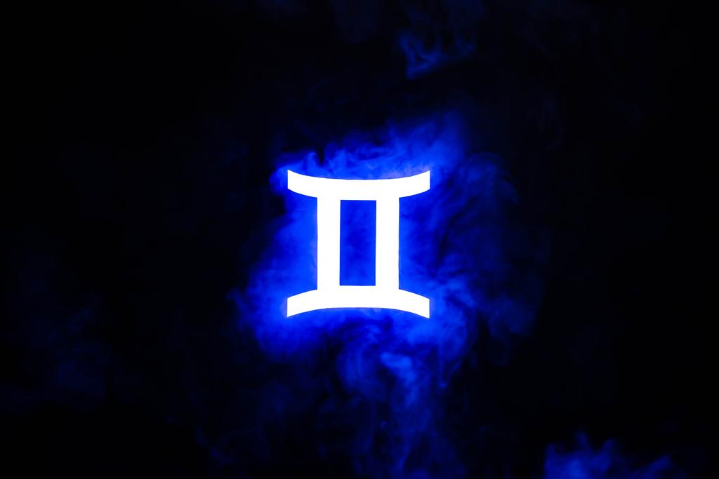 blue illuminated Gemini zodiac sign with colorful smoke on background - Photo, Image