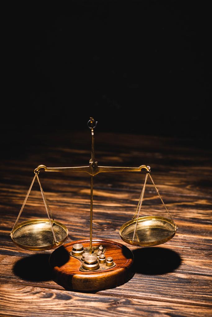 золоті шкали справедливості на дерев'яному столі на чорному тлі
 - Фото, зображення