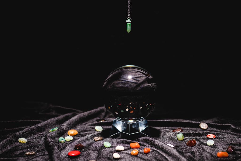 fortuin vertellen steen boven kristallen bol op zwart fluweel doek geïsoleerd op zwart - Foto, afbeelding