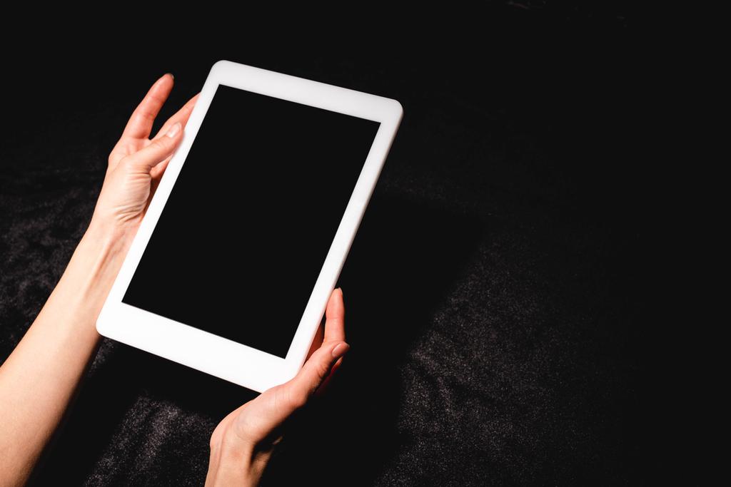 vista recortada da mulher segurando tablet digital com tela em branco no pano de veludo preto
 - Foto, Imagem