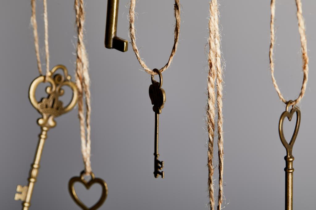 close up view of vintage keys hanging on ropes isolated on grey - Photo, Image
