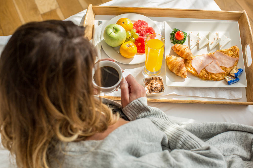 Приваблива жінка снідає в готельному ліжку
 - Фото, зображення
