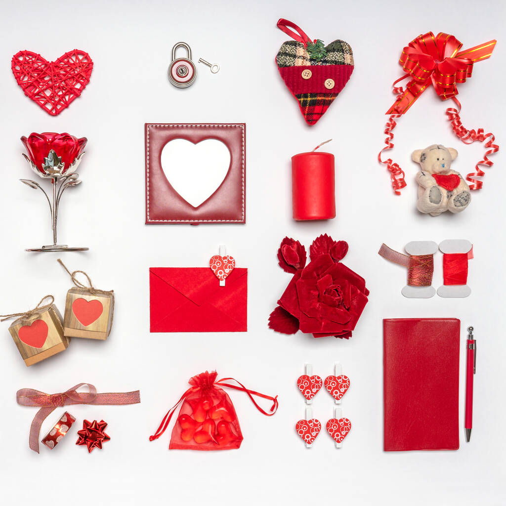 Elegantes accesorios, artículos decorativos y juguetes en miniatura en color rojo sobre fondo blanco. Fotograma vacío, maqueta. Tarjeta de felicitación para el día de San Valentín, el amor y el concepto romántico. Copiar espacio - Foto, Imagen