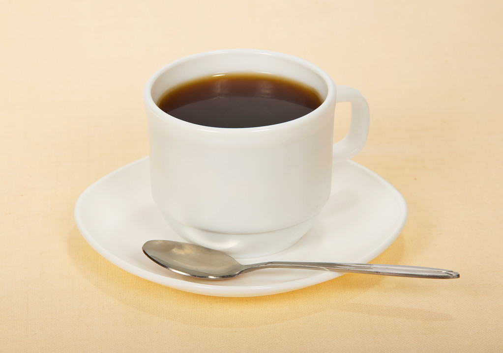 Kaffee in einer Tasse mit Untertasse, auf beigem Hintergrund - Foto, Bild