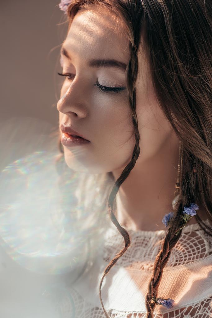tender girl with braids in hairstyle posing in white boho dress on grey with lens flares  - Photo, Image