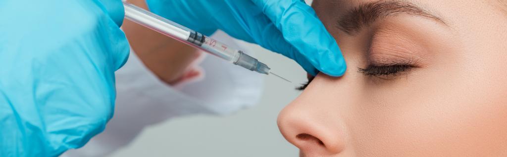 panoramatický záběr kosmetolog dělat krása injekce atraktivní žena izolované na šedé - Fotografie, Obrázek