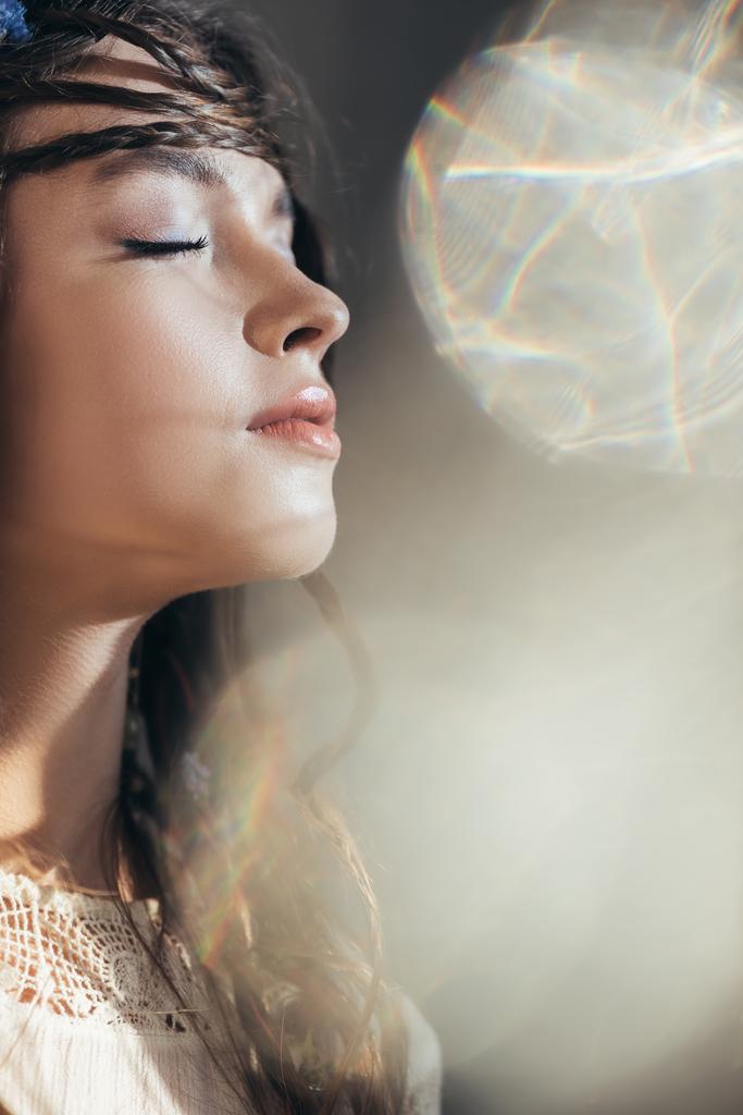 menina boho atraente com tranças no penteado posando com olhos fechados em cinza com flares de lente
  - Foto, Imagem