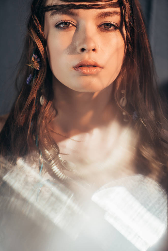 menina boho atraente com tranças no penteado posando em cinza com flares de lente
  - Foto, Imagem
