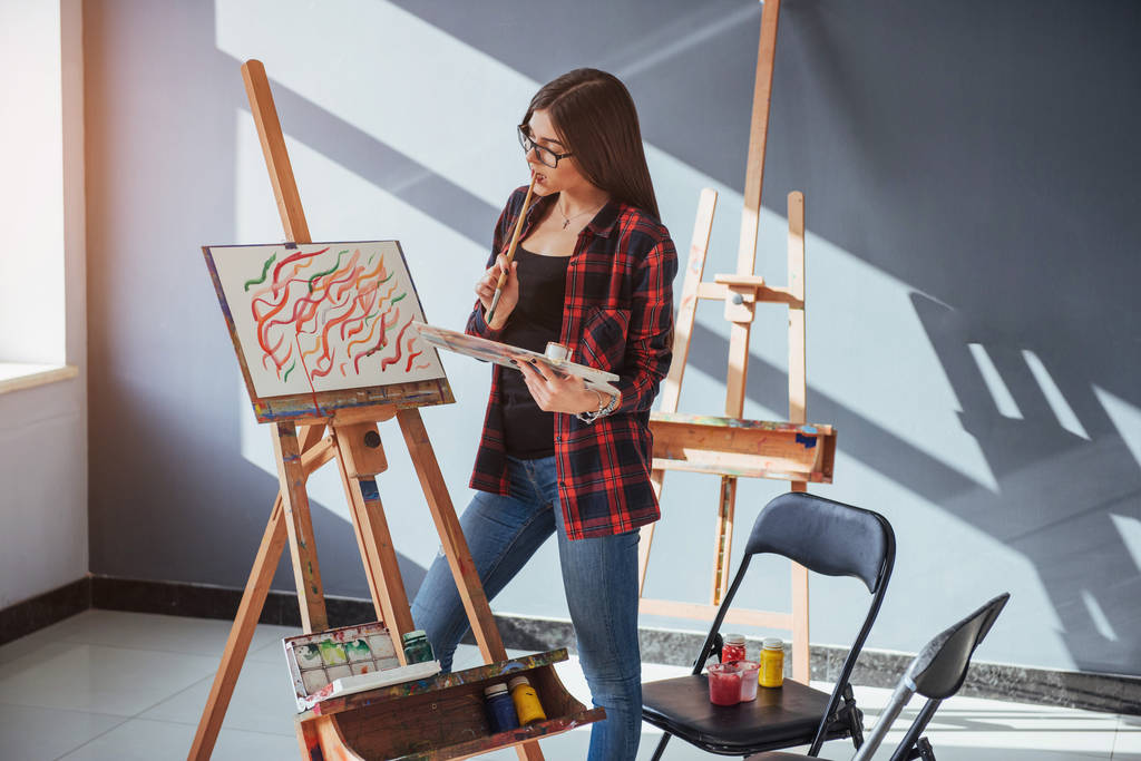 hübsche hübsche Künstlerin malt auf Leinwand auf der Staffelei. Modell im Atelier - Foto, Bild