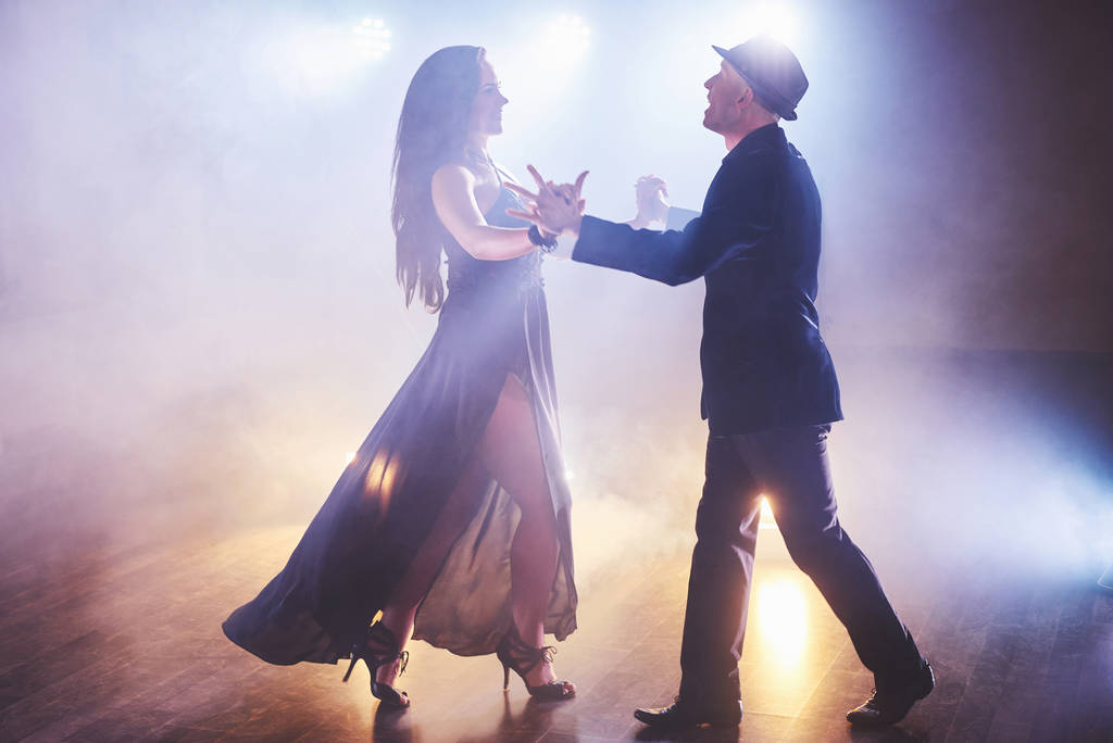 Geschickte Tänzer, die im dunklen Raum unter dem Licht und Rauch des Konzerts auftreten. sinnliches Paar, das einen künstlerischen und emotionalen zeitgenössischen Tanz aufführt. - Foto, Bild