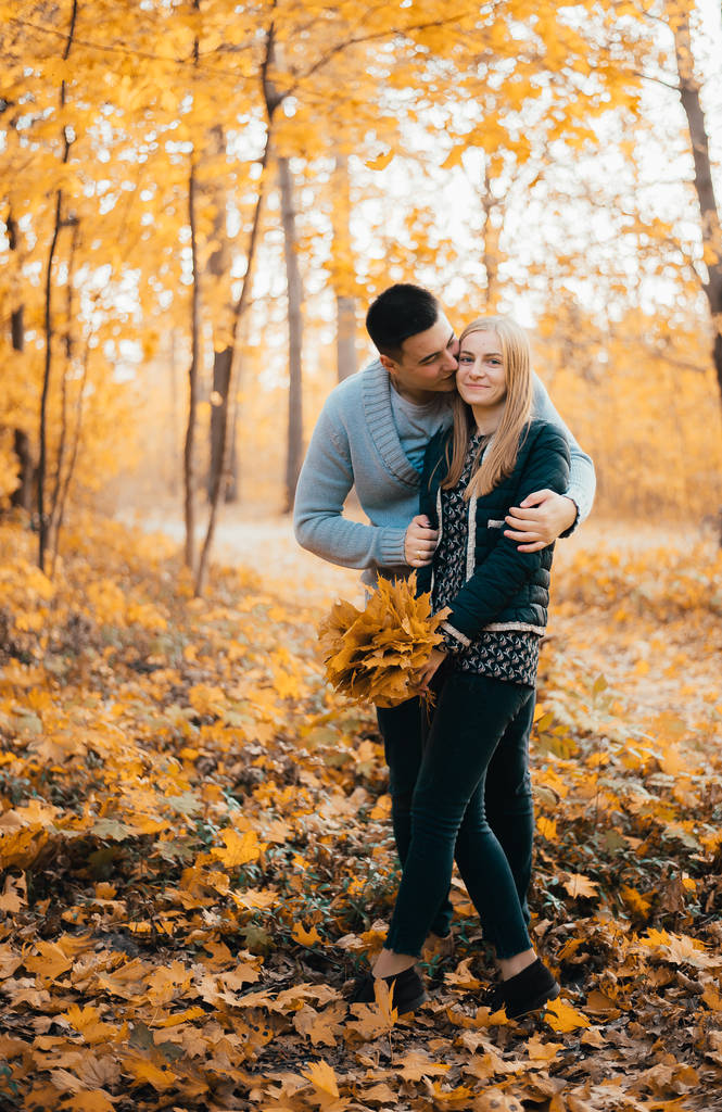 piękna szczęśliwa młoda para stojąca razem i przytulająca się w jesiennym lesie - Zdjęcie, obraz