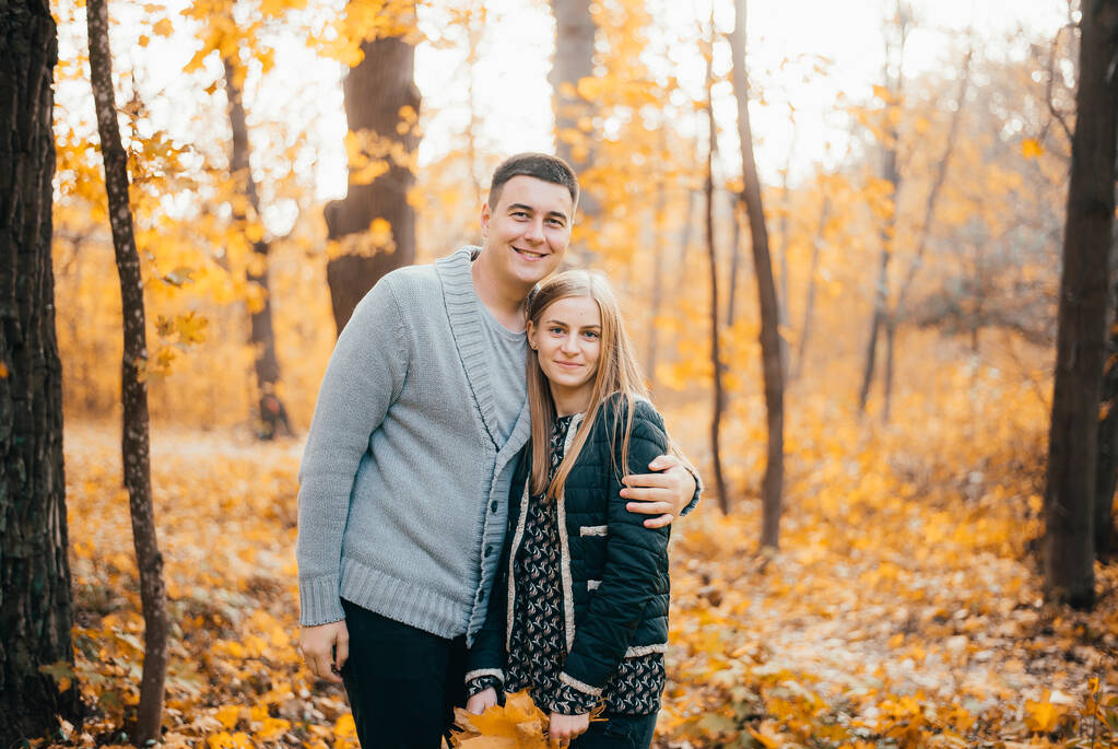 belo feliz jovem casal de pé juntos e abraçando no parque de outono
 - Foto, Imagem