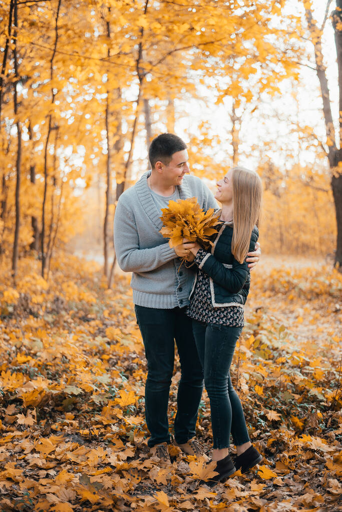 schönes glückliches junges Paar steht zusammen und umarmt sich im Herbstwald - Foto, Bild