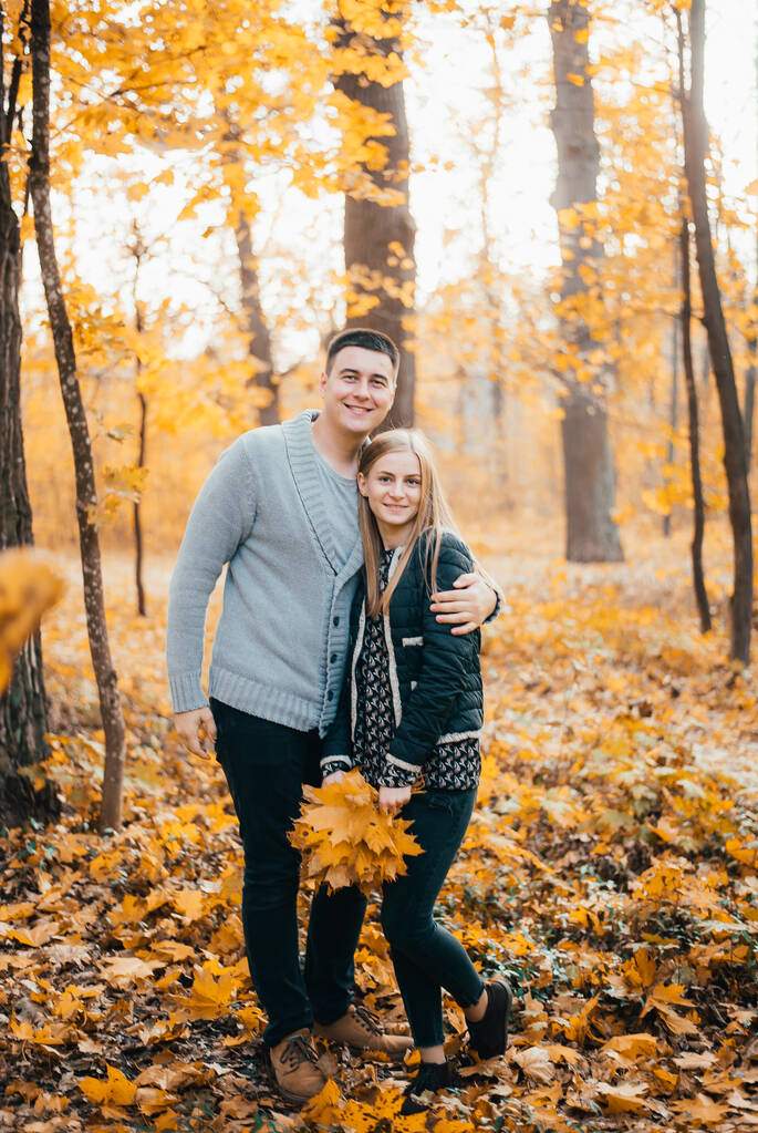 hermosa pareja joven feliz de pie juntos y abrazándose en el parque de otoño
 - Foto, imagen