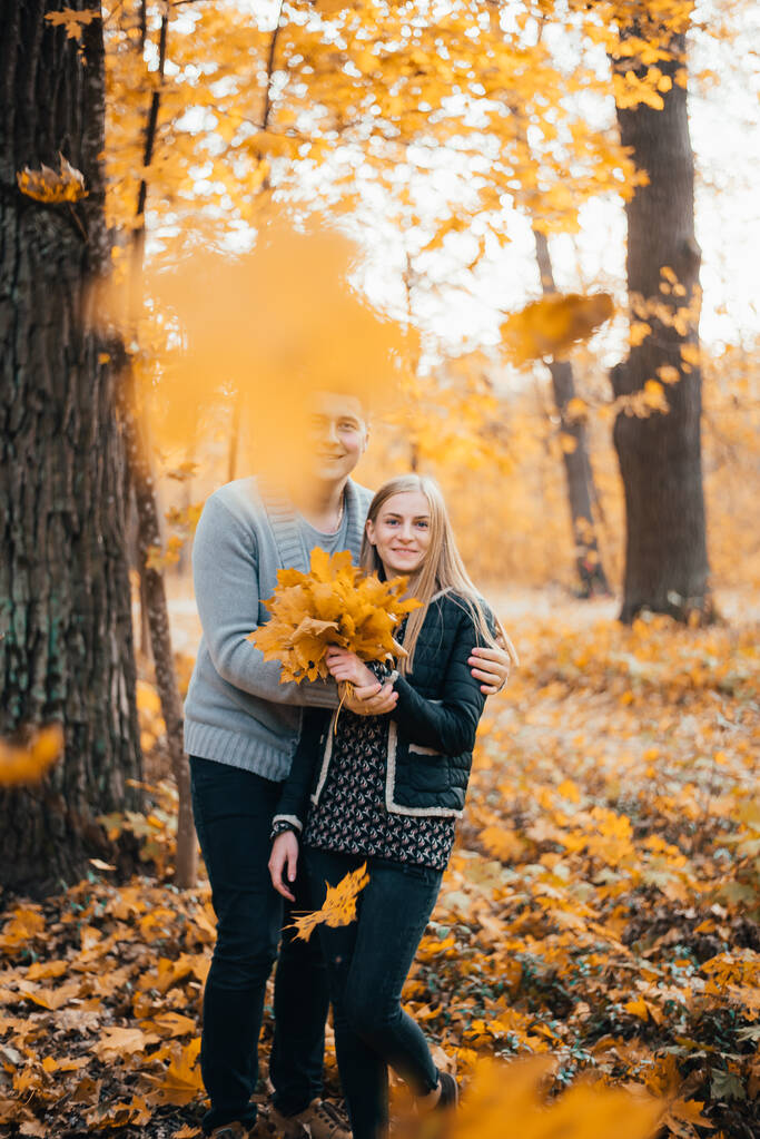 beautiful happy young couple standing together and hugging in autumn forest - Photo, Image
