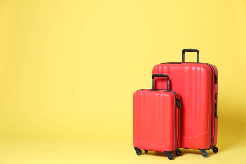黄色の背景にスタイリッシュな赤いスーツケース。テキストのスペース - 写真・画像