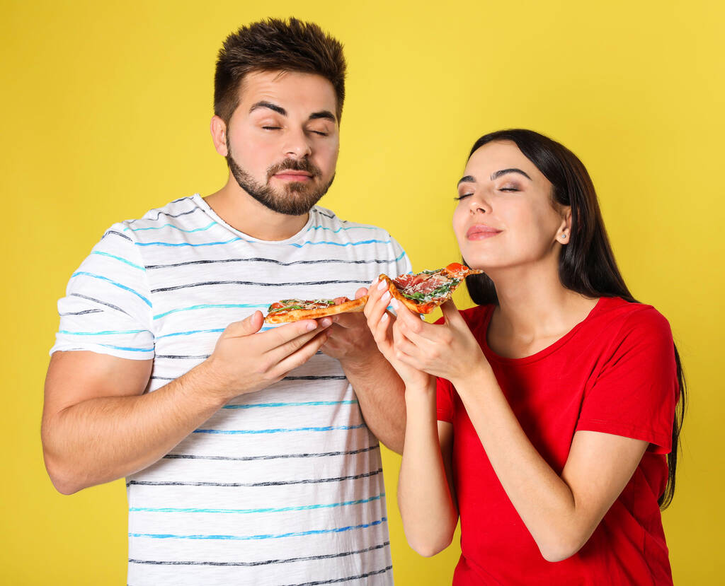 Emotioneel koppel met pizza op gele achtergrond - Foto, afbeelding