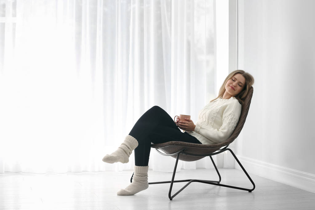 Nuori nainen lepää nojatuolissa kotona. Tekstitila
 - Valokuva, kuva