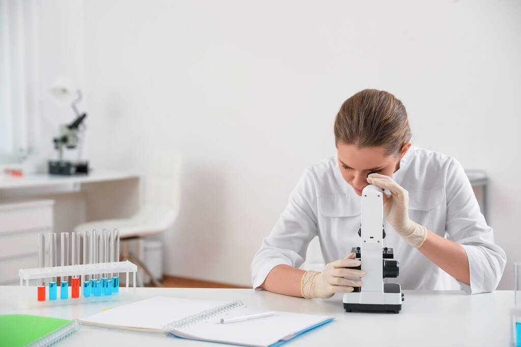Επιστήμονας που χρησιμοποιεί σύγχρονο μικροσκόπιο στο τραπέζι. Ιατρική έρευνα - Φωτογραφία, εικόνα